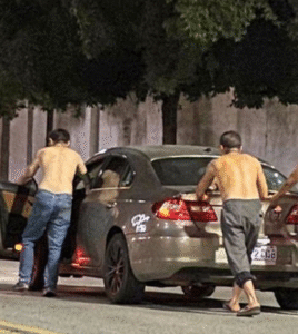 Três amigos evitam dirigir bêbados, empurram carro e acabam multados por bloquear a estrada.