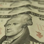 Dólar cai abaixo de R$ 5 após Flávio Bolsonaro liderar 1º turno